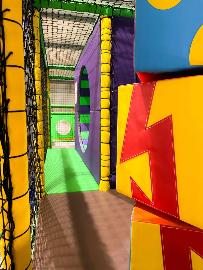 Colourful Totem Pole and green and purple vortex wheel at Cannon Hall Farm's indoor softplay area. Designed by Play Creations.