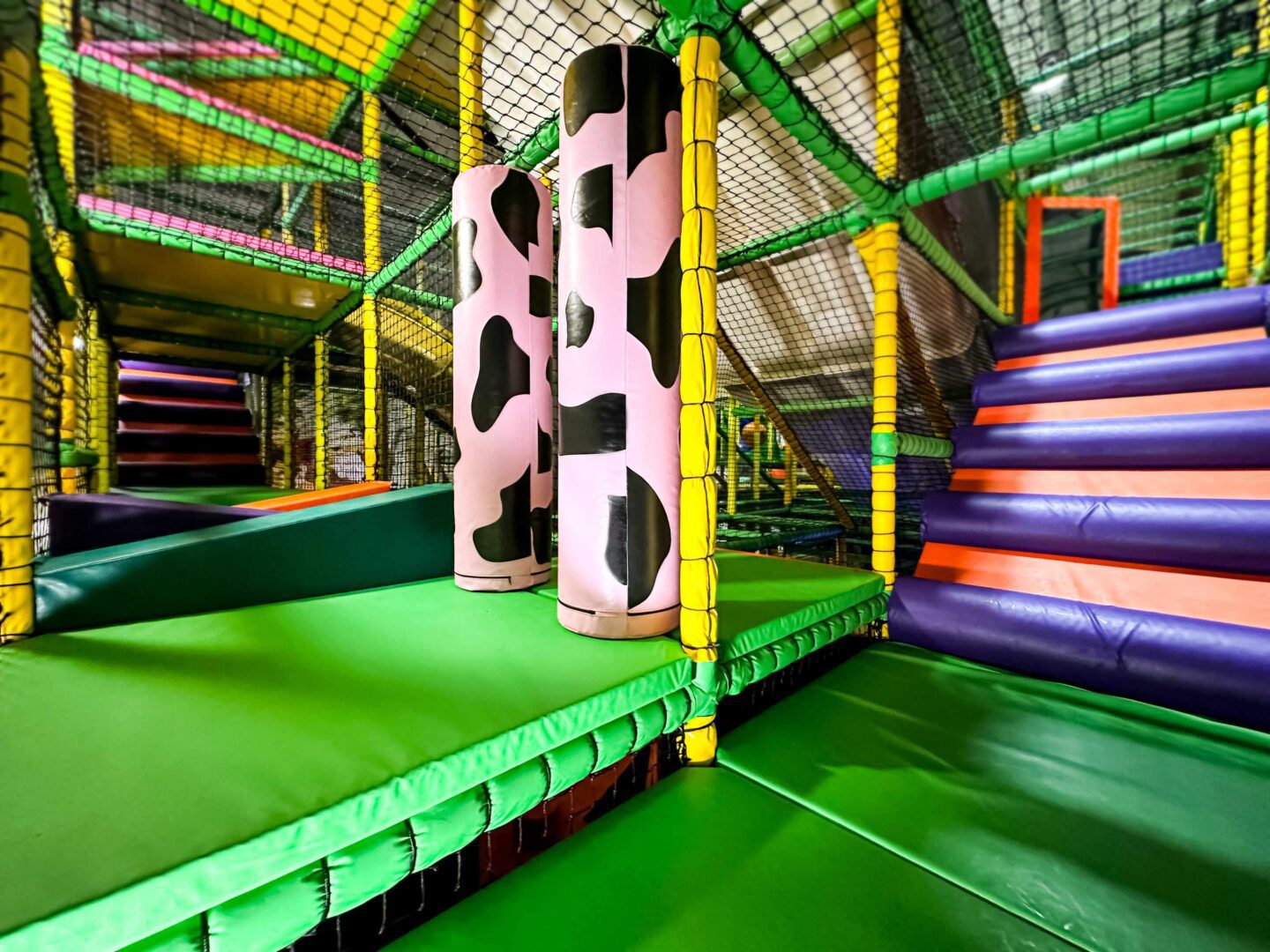 Custom pink and black cow-print vertical rollers with an orange and purple log ramp in the background. These are inside Cannon Hall Farm's indoor softplay area designed by Play Creations.