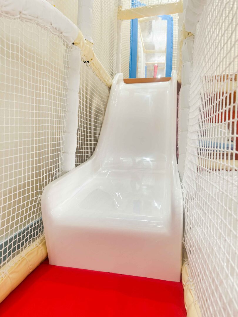 White toddler slide found at It Takes a Village's indoor softplay, designed by Play Creations