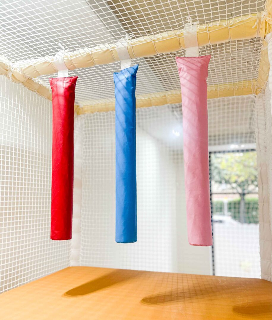 Red, blue, and pink hanging snakes at It Takes a Village's indoor softplay area. Designed by Play Creations