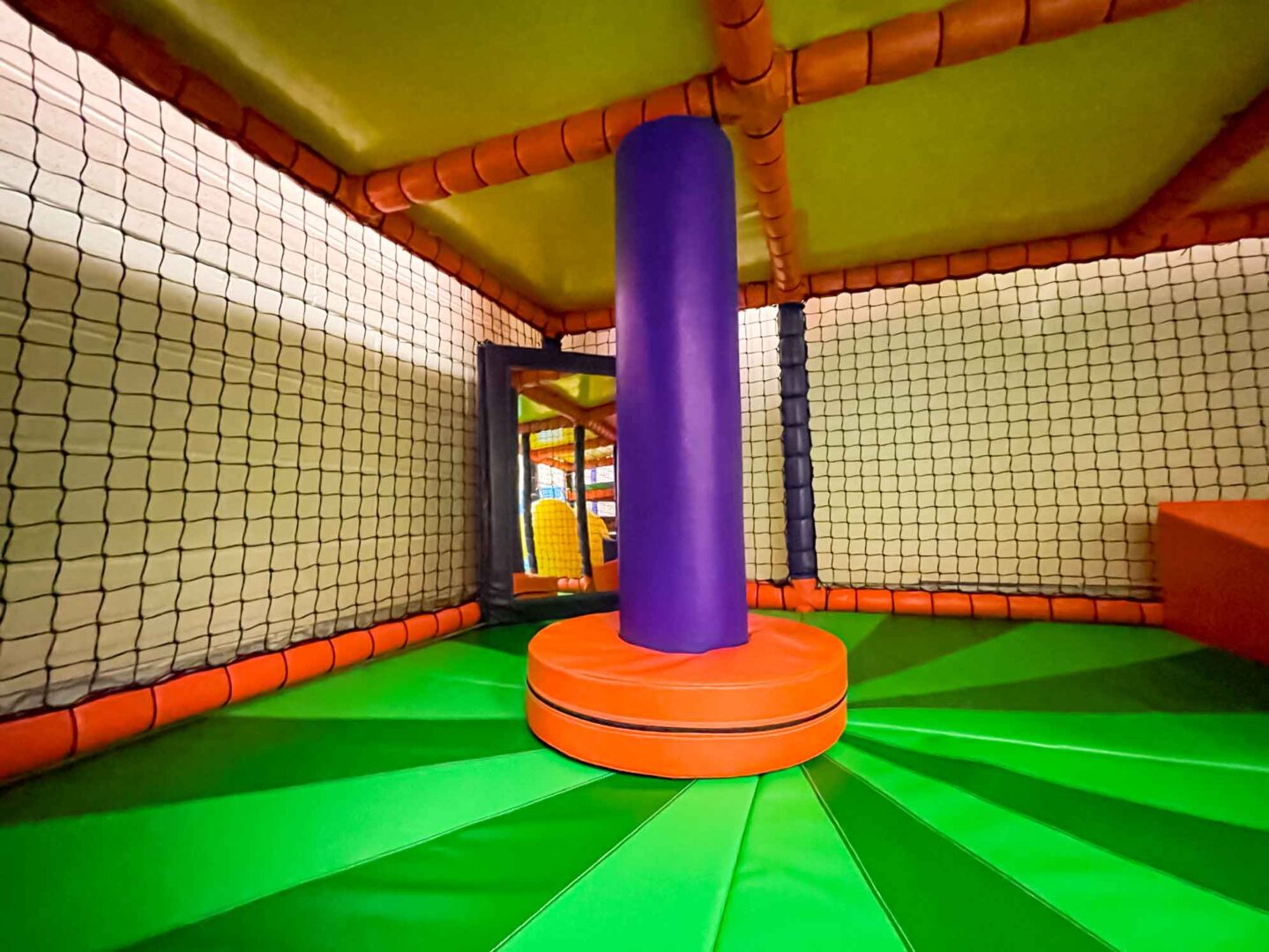 Orange and purple dizzy disk with a two-toned green applique floorboard at St Giles indoor softplay area