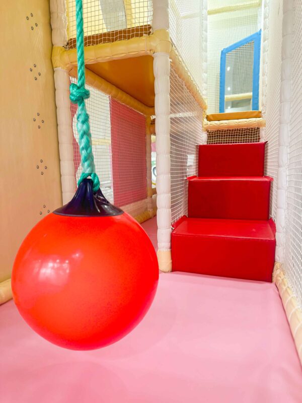 Red Swinging Buoy at It Takes a Village's indoor softplay area with red step blocks in the background.