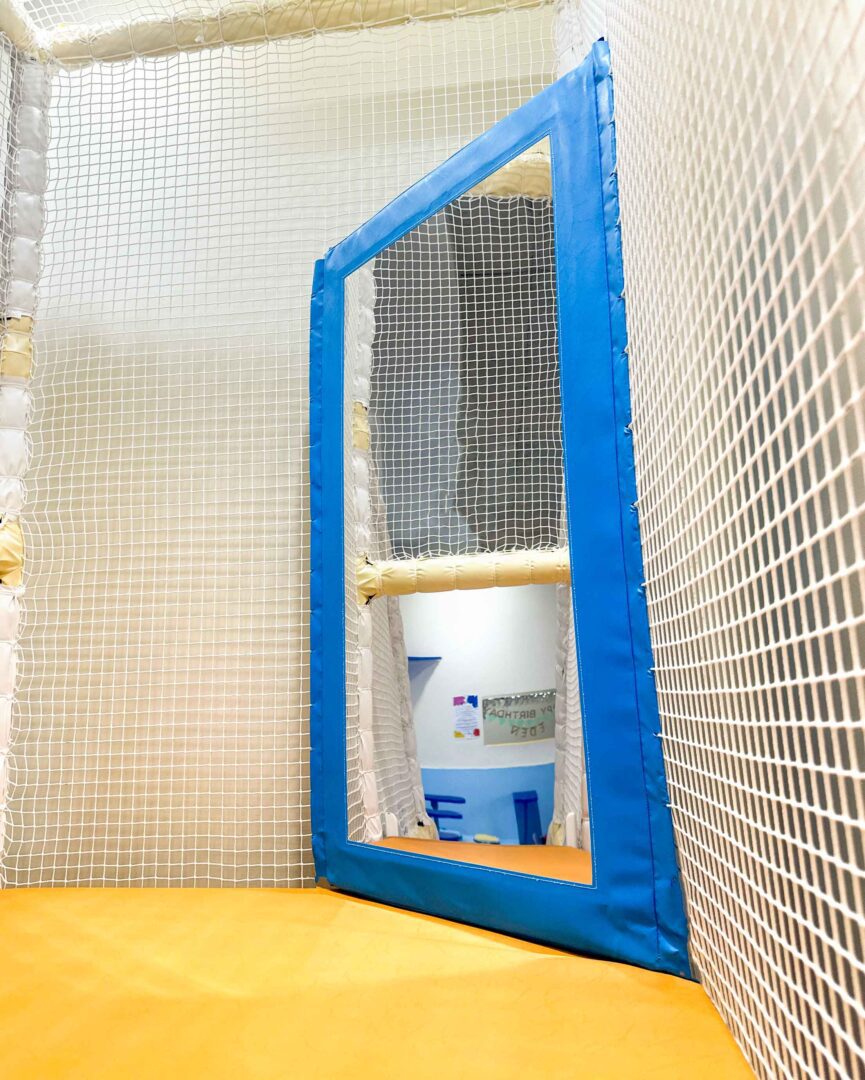 Blue Corner Mirror surrounded by white netting at It Takes a Village's Indoor Softplay Area