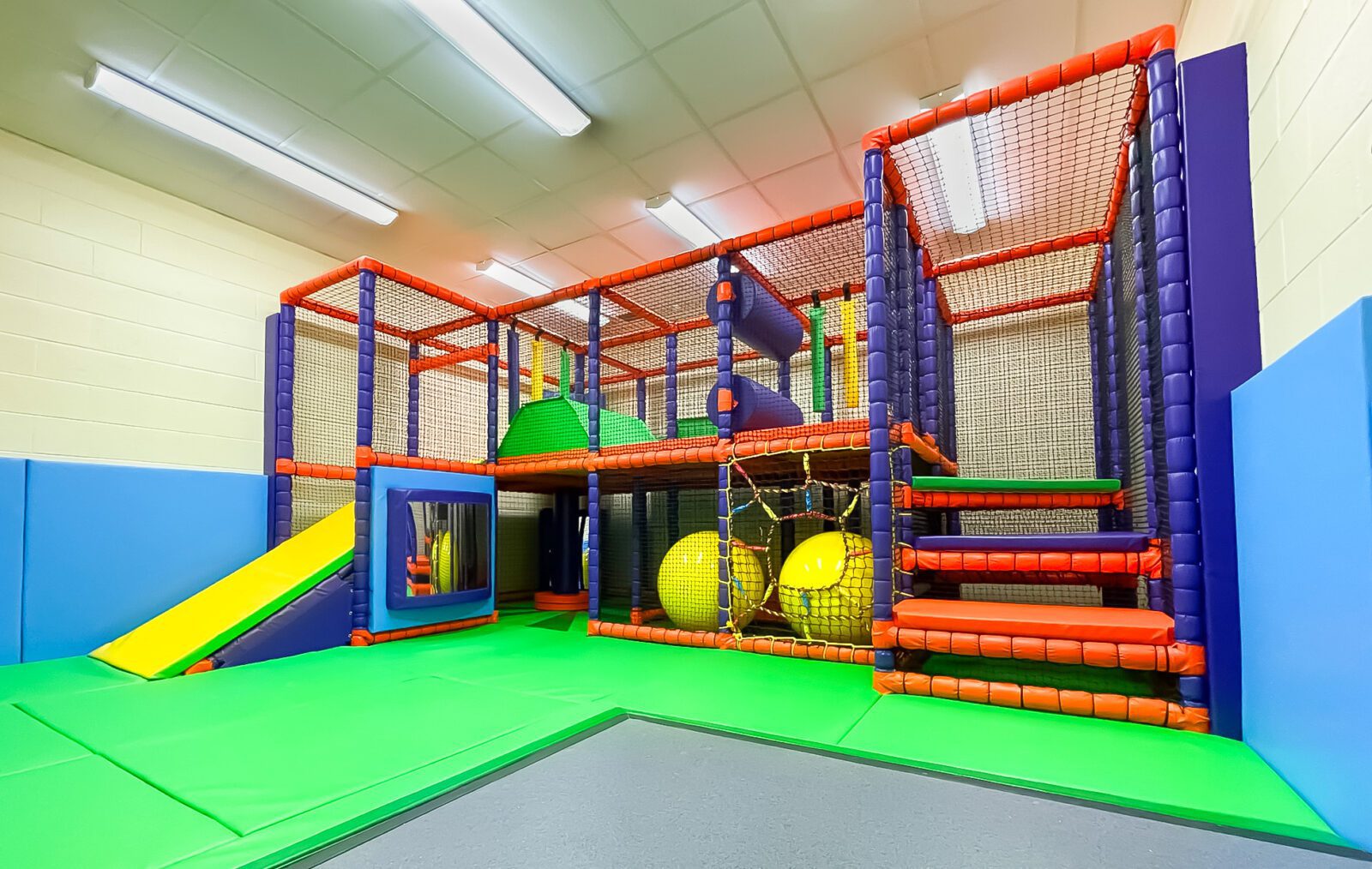 Finished full view of softplay at St Giles School. The colour scheme is green, yellow, orange and purple and brings in bright bold tones for the school. Designed by Play Creations.