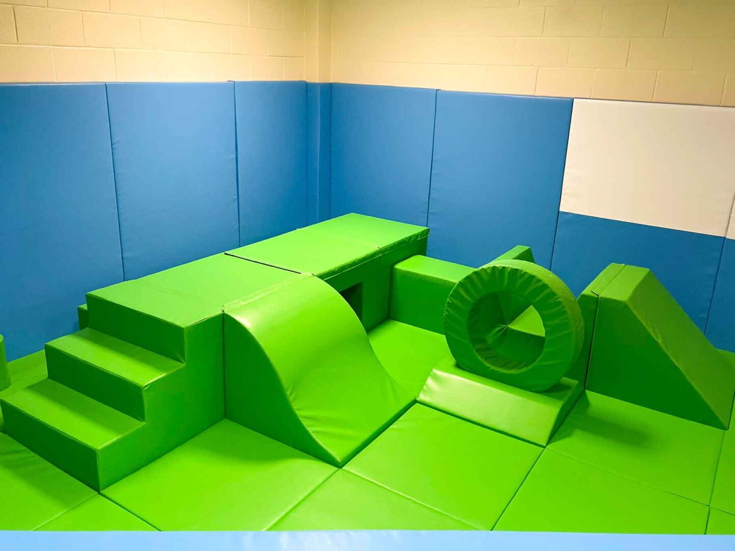 Full view of Movement area at St Giles School designed by Play Creations. The area covers a corner of the room and features a green and blue theme.