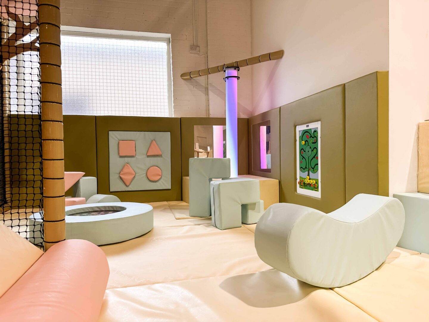 This is the sensory and baby area in Play Hut's indoor softplay area. There is an LED light tube and various soft play blocks. The theme is pink, blue and green. Designed by Play Creations