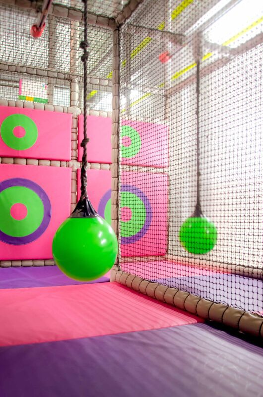 2x Ariel Glides and Splat Pads at Fun Factory's indoor softplay area. The colour scheme for these are green, purple and pink.
