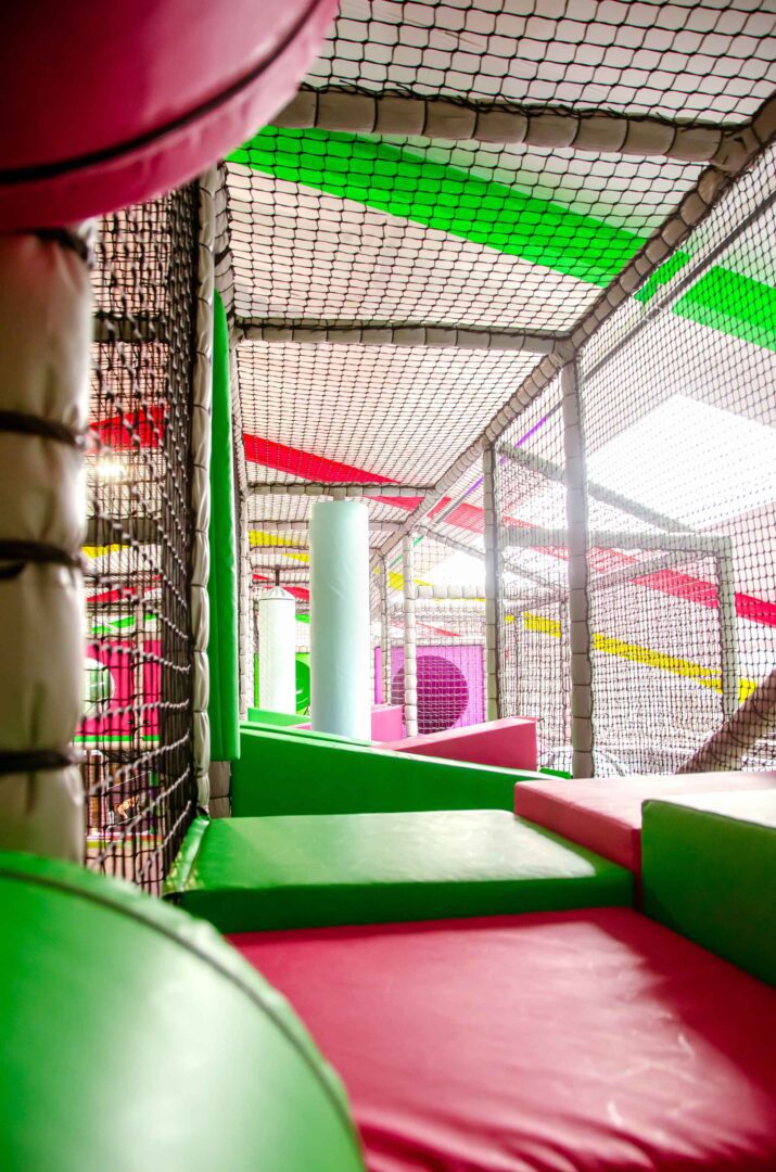 This is the green and pink wedge flooring at Fun Factory's indoor softplay. In the background there is a white vertical roller seperating the first set of floors from the second set.